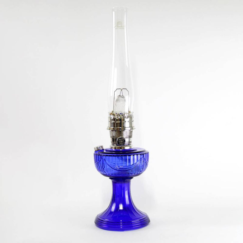 Unique handcrafted cobalt oil lamp with Lincoln drape font design, featuring brass burner and tall clear chimney, ideal for Lamps & Lighting, Oil Lamps, Table Lamps, Best Sellers, and Promo Eligible collections.
