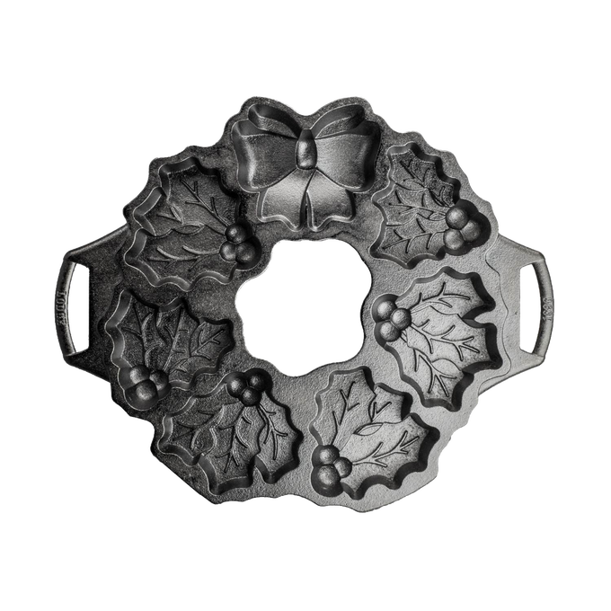 Seasoned cast iron cakelet pan shaped like a holiday wreath with holly leaves, berries, and bow details, ideal for even baking in Kitchen & Food and Cast Iron collections.