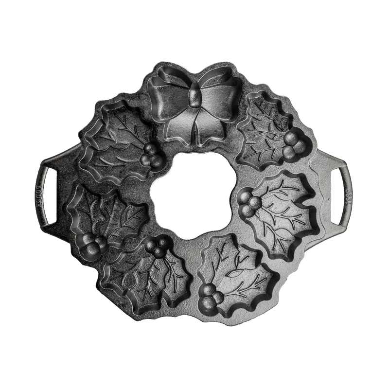 Seasoned cast iron cakelet pan shaped like a holiday wreath with holly leaves, berries, and bow details, ideal for even baking in Kitchen & Food and Cast Iron collections.