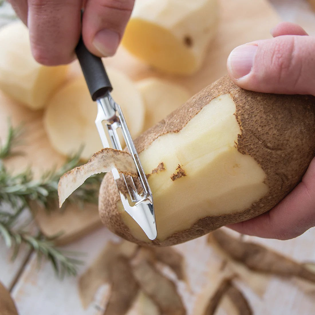 Handcrafted vegetable peeler with razor-sharp stainless steel blade and durable black resin handle peeling a russet potato, perfect for Kitchen & Food, Specialty Equipment, Peelers and Pitters, USA Made, Best Sellers, Promo Eligible collections.