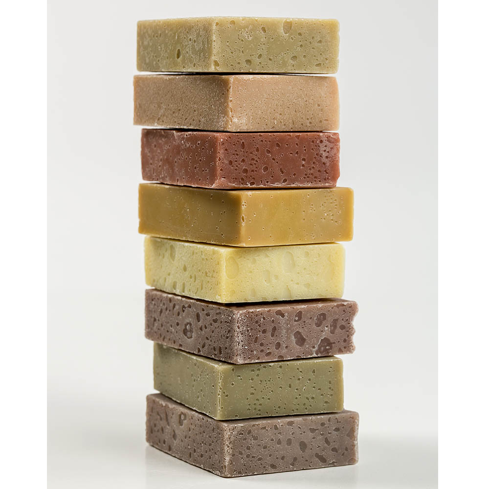 Stack of seven handcrafted natural soap bars in varying earthy colors, showcasing a unique variety pack for Health & Wellness, Soaps and Soapmaking, USA Made, and Best Sellers collections.