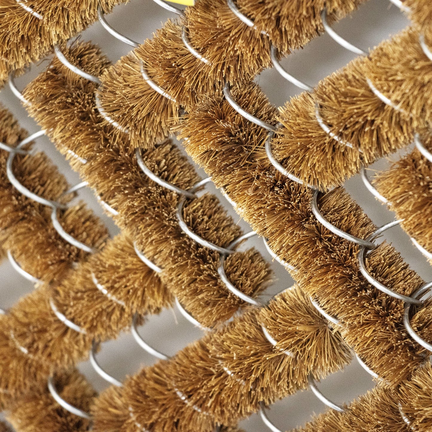 Close-up of natural coconut fiber bristles arranged in rows on wire frames, part of a handcrafted bootscraper rug for cleaning shoes, featured in Home & Decor and Best Sellers collections.