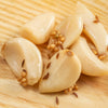 Close-up of several cloves of lightly pickled garlic sprinkled with spices on a wooden surface, showcasing a handcrafted Ohio Amish made product from the Kitchen & Food Pantry collections.