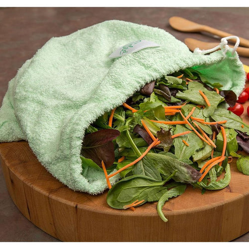 Light green super absorbent fabric lettuce storage bag with drawstring partially open on wooden cutting board, filled with mixed salad greens and shredded carrots, ideal for Kitchen & Food and Storage and Serving collections.