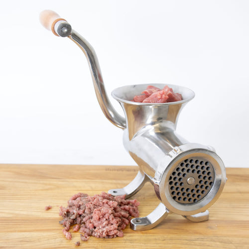 Handcrafted stainless steel meat grinder with wooden handle, secured on wooden surface, processing fresh meat, featured in Kitchen & Food, Specialty Equipment, Butchering Supplies, Best Sellers collections.