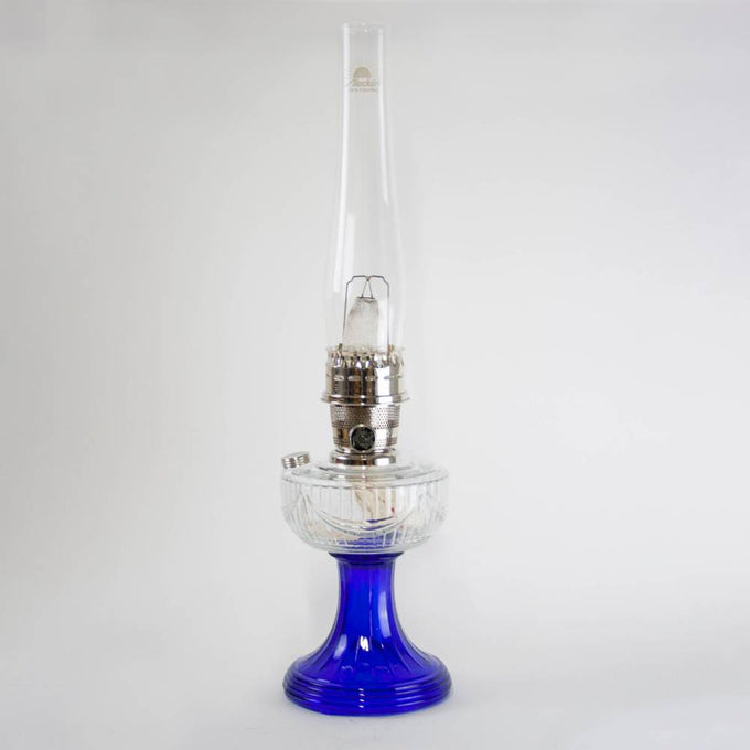Handcrafted oil lamp featuring a vibrant cobalt glass base and clear glass chimney with brass trim, ideal for Lamps & Lighting, Oil Lamps, Table Lamps, Best Sellers, and Promo Eligible collections.