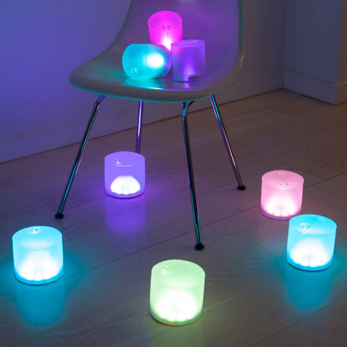 Set of glowing inflatable LED solar lights in various pastel colors arranged on a chair and hardwood floor, ideal for camping, emergency supplies, and outdoor lighting.