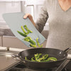 Person using a compact, space-saving chopping board with easy-pour ends to transfer sliced green bell peppers into a black frying pan, ideal for Kitchen & Food and Food Prep collections.