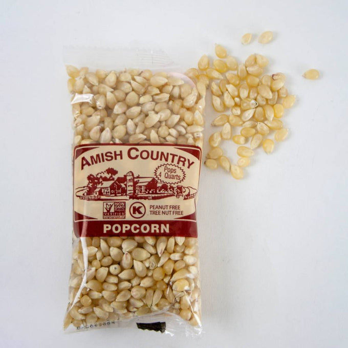 Clear plastic bag of Amish Country popcorn kernels in pale yellow hues with a few kernels spilled beside it, highlighting handcrafted, USA made popcorn in Kitchen & Food and Snacks collections.
