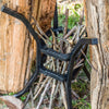 Handcrafted sturdy cast iron fire and cook stand holding stacked small sticks against a backdrop of wood logs in an outdoor setting, ideal for Farm, Garden & Tool, Camping, Best Sellers, and Promo Eligible collections.