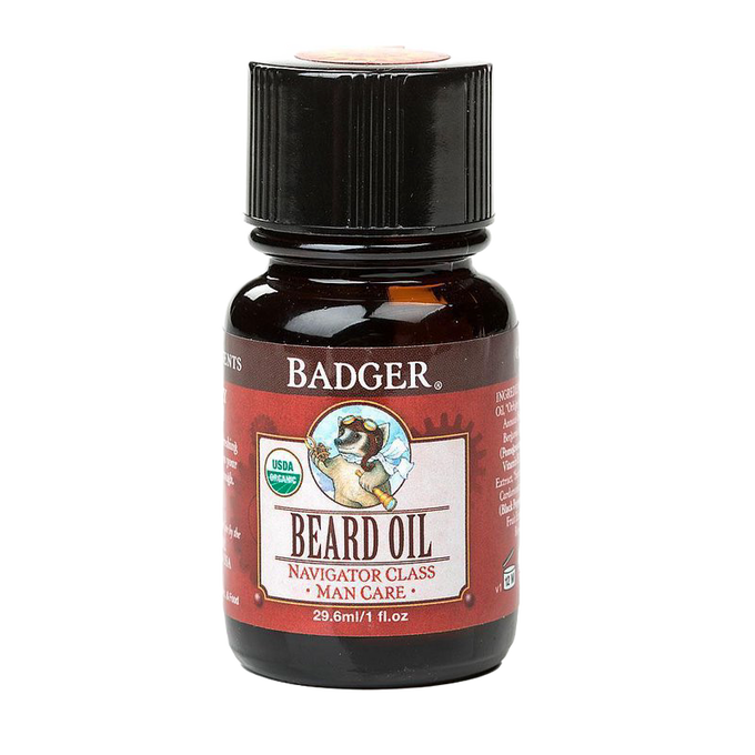 Dark amber glass bottle with black cap containing handcrafted beard oil, featuring an illustrated badger logo and red label, made in USA for grooming and personal care.