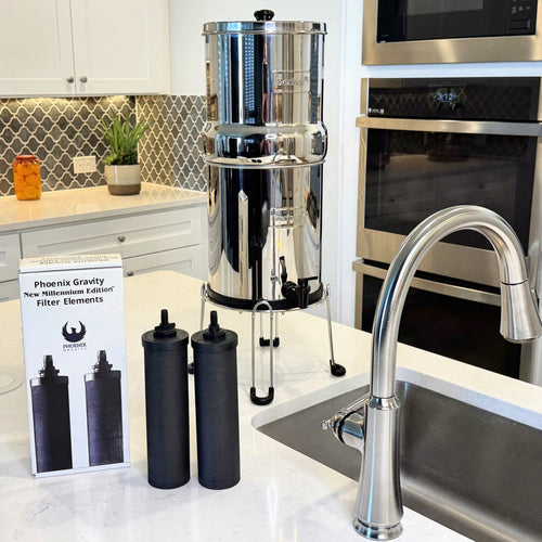 Two black gravity filter elements standing next to their white packaging box in a modern kitchen with a stainless steel gravity water filter and faucet, suitable for Appliances, Water Heating and Treatment, Best Sellers, Promo Eligible, Berkey Water Filters, and All Stoves & Appliances collections.