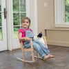Young child sitting barefoot in a handcrafted wooden rocker made of unfinished solid oak, holding a stuffed animal indoors, showcasing exclusive Amish-made quality for Toys, Books & Games and USA Made collections.