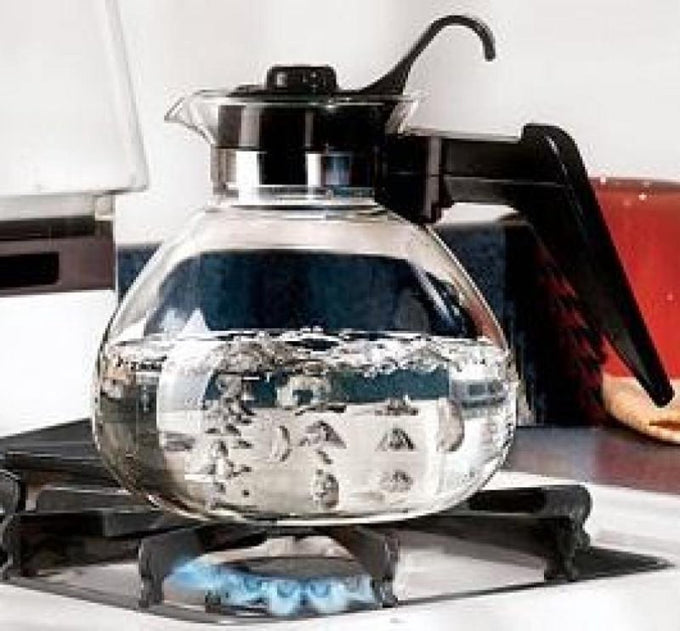 Clear borosilicate glass teakettle with black handle and lid boiling on a gas stove, designed for Kitchen & Food and Brewing Coffee and Tea collections.
