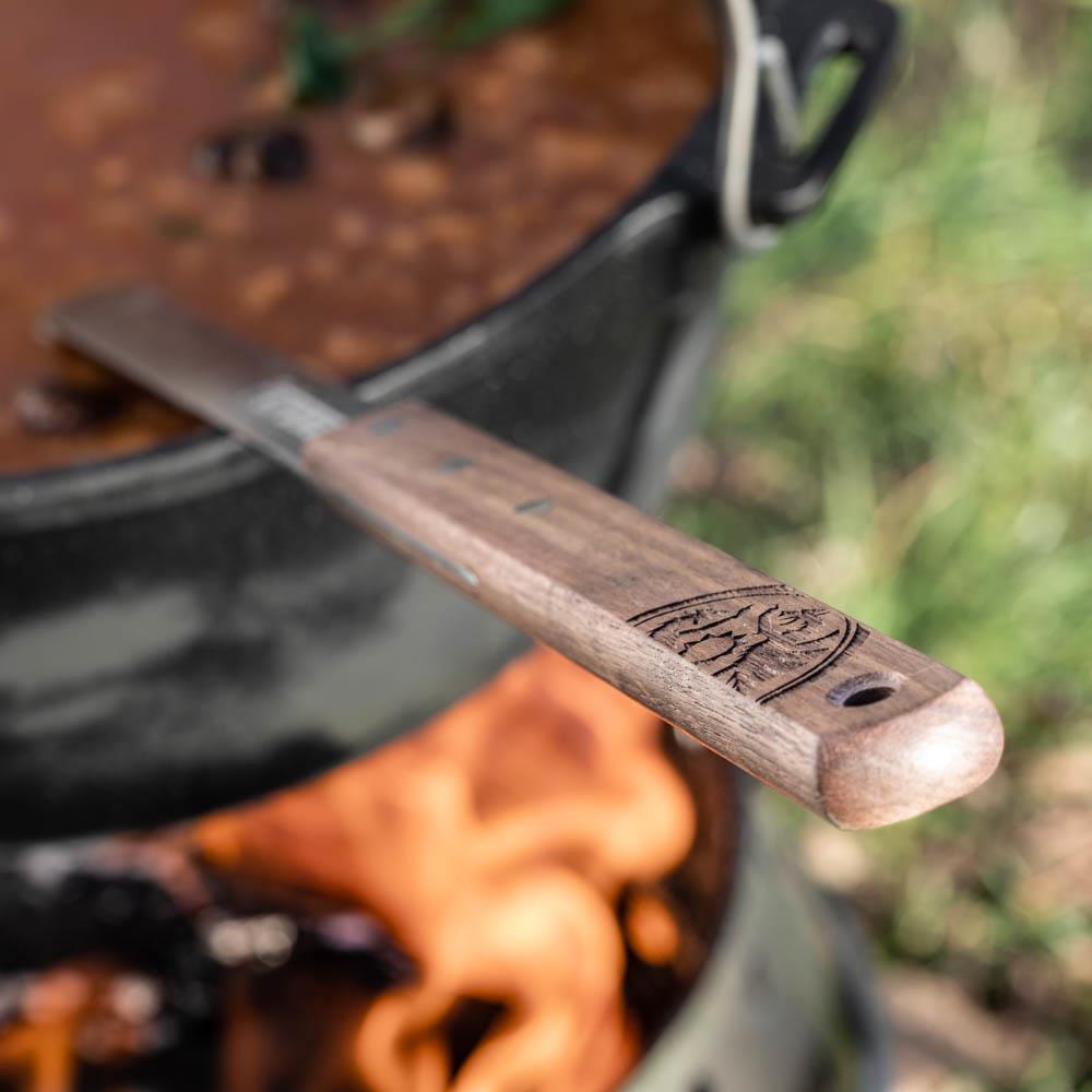 Close-up of a handcrafted wooden handle with engraved logo and hanging hole on a stainless steel soup ladle, designed for outdoor use in Farm, Garden & Tool, Camping, and Kitchen & Food collections.