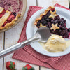 Handcrafted stainless steel ice cream scoop with a stub-nose end resting beside a slice of star-topped berry pie and melting vanilla ice cream on a white plate, featured in Kitchen & Food, Specialty Equipment, Making Ice Cream, Storage and Serving, USA Made, and Best Sellers collections.