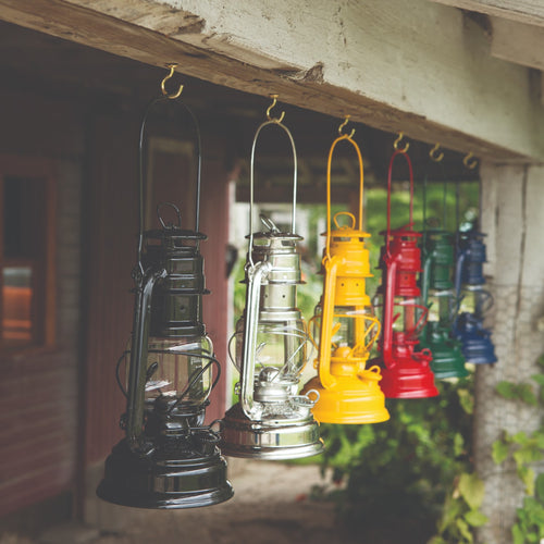 Handcrafted galvanized oil lanterns in black, silver, yellow, red, green, and blue, hanging from rustic beam outdoors, ideal for Lamps & Lighting, Camping, and Emergency Supplies collections.
