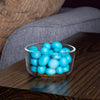 Small clear bowl filled with bright blue coated chocolate-covered blueberries on a dark wooden surface, showcasing a handcrafted treat ideal for Kitchen & Food and Snacks and Sweets collections.