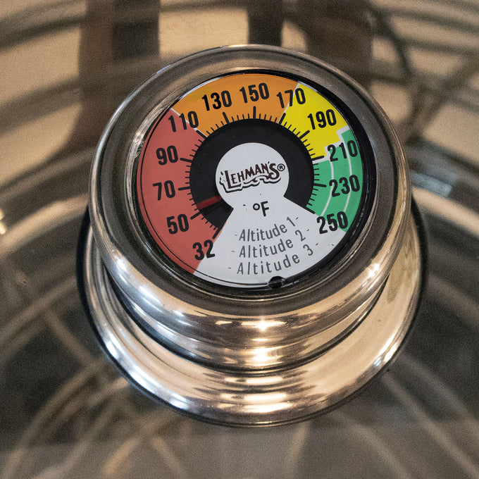 Close-up of a handcrafted built-in temperature gauge on a stainless steel water bath canner lid, featuring color-coded heat zones for precise control in kitchen, food preservation, and canning.