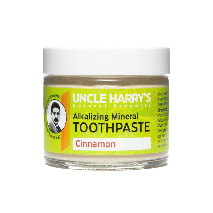 Small glass jar of handcrafted alkalizing mineral toothpaste in cinnamon flavor with a bright yellow label, promoting natural health and wellness and American-made grooming care.
