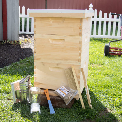 Amish-crafted natural wood 10-frame beehive with essential beekeeping tools including smoker, brush, frame grip, hive tool, and bee feeder, set outdoors on green grass, ideal for Farm, Garden & Tool, 10-Frame Hives and Components, Beekeeping Supplies, Best Sellers, and Promo Eligible collections.