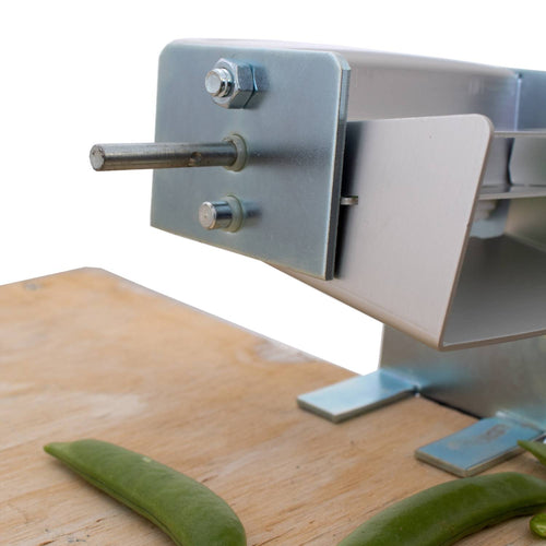 Close-up of a metal pea sheller with a clamp base attached to a wooden surface, featuring a sturdy shaft for hand or motorized use, suitable for Kitchen & Food, Specialty Equipment, Peelers and Pitters, USA Made, Best Sellers, and Promo Eligible collections.