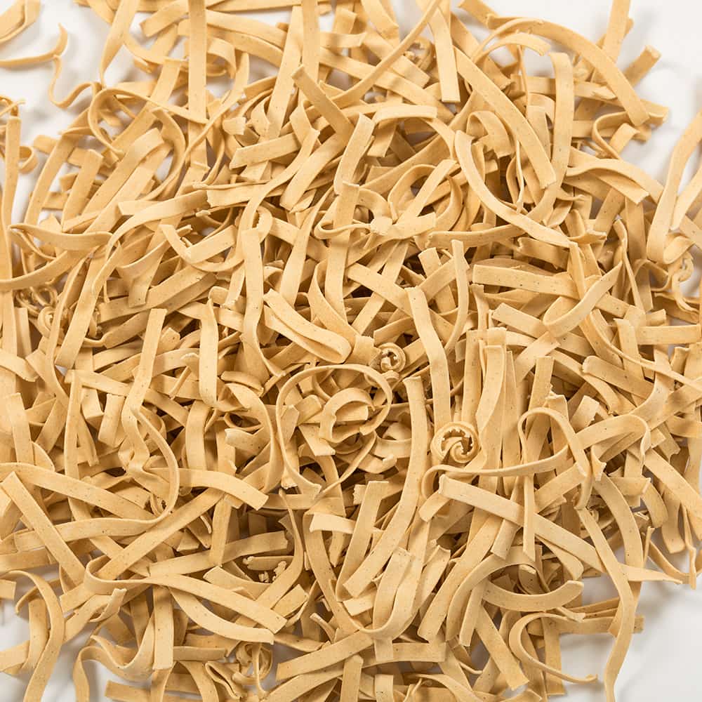 Close-up of uncooked gluten-free homestyle noodles in a loose pile, showcasing their natural beige color and traditional egg noodle texture, part of Kitchen & Food, Pantry, and USA Made collections.