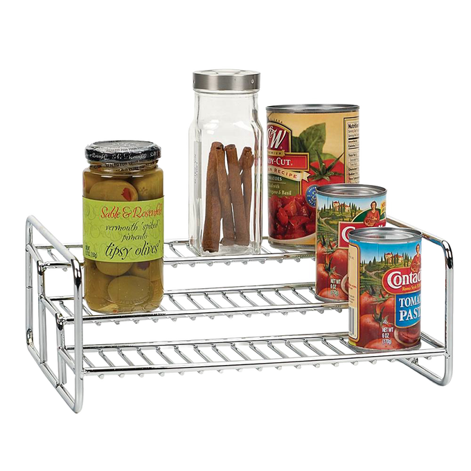 Chrome-finished 3-tier rack holding assorted pantry items including a jar of olives, a spice container with cinnamon sticks, and several canned goods, ideal for kitchen organization and storage.