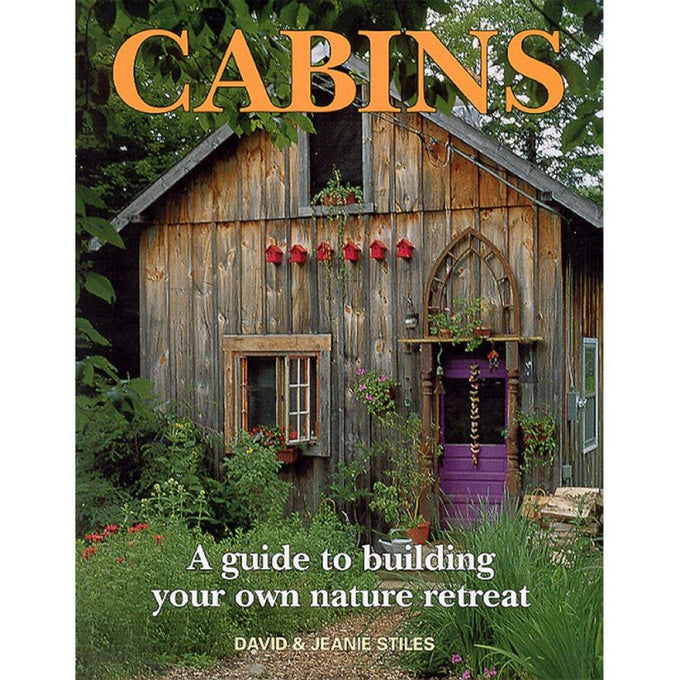 Rustic wooden cabin with weathered vertical planks, a purple door framed by decorative woodwork, surrounded by lush greenery and flowering plants, featured in Toys, Books & Games and Home and Garden How-To Books collections.