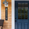 Slim vertical black and silver custom address plaque with modern white numbers mounted on wooden siding beside a blue door, handcrafted in USA, featured in Home & Decor and Mailboxes and Address Signs collections.