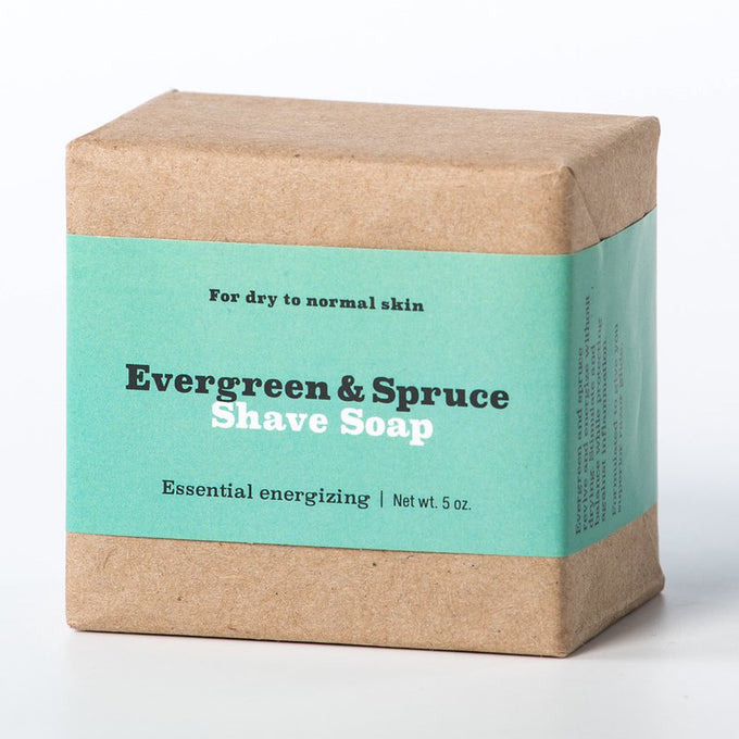 Handcrafted soap bar wrapped in natural kraft paper with a teal label highlighting evergreen and spruce shave soap for dry to normal skin, USA Made, featured in Health & Wellness and Grooming collections.