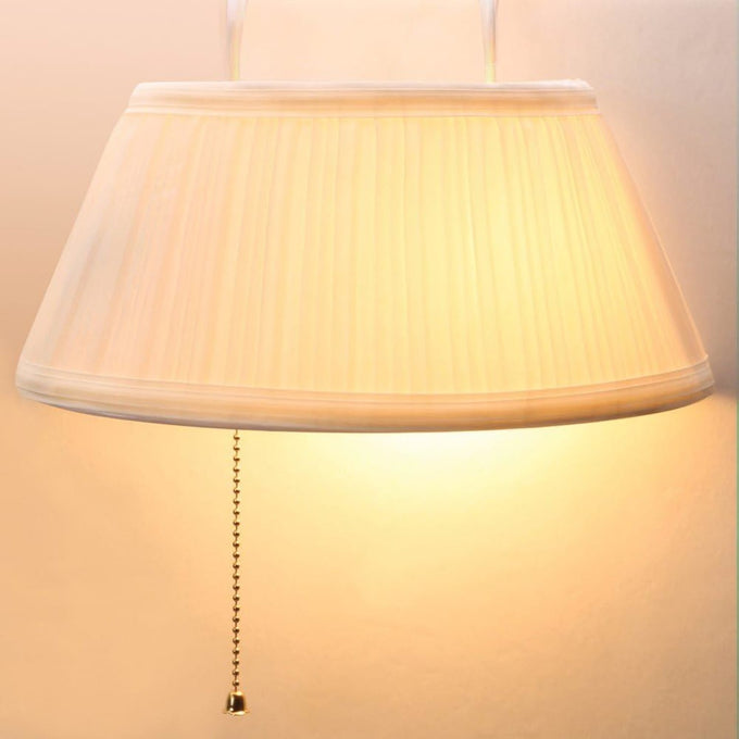 Cream-colored pleated fabric lampshade with pull chain hanging softly, designed for easy bedside lighting in home, camping, and outdoor electric light collections.