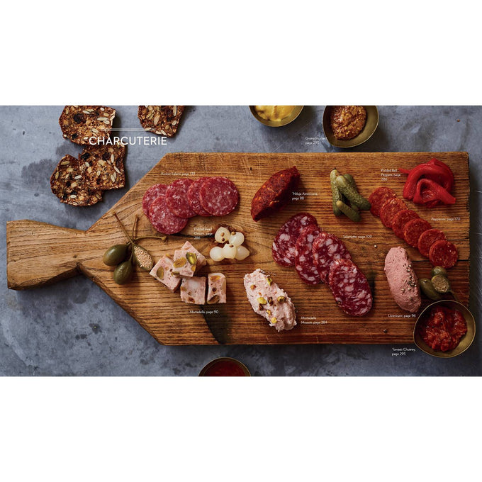 Wooden cutting board with an assortment of sliced cured meats, pâté, pickles, and crackers arranged in a handcrafted rustic style, suitable for cookbooks, best sellers, and home and garden how-to collections.