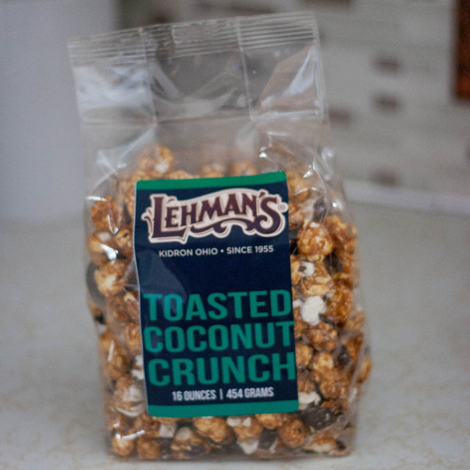 Clear bag of handcrafted caramel popcorn with toasted coconut flavor, a unique sweet and crunchy snack made in USA, featured in Kitchen & Food, Snacks and Sweets, Popcorn, USA Made, and Best Sellers collections.