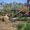 Handcrafted steel broadfork with five sharp angled tines and red handles being used to loosen soil in a garden, ideal for Farm, Garden & Tool and Digging and Cultivating collections.