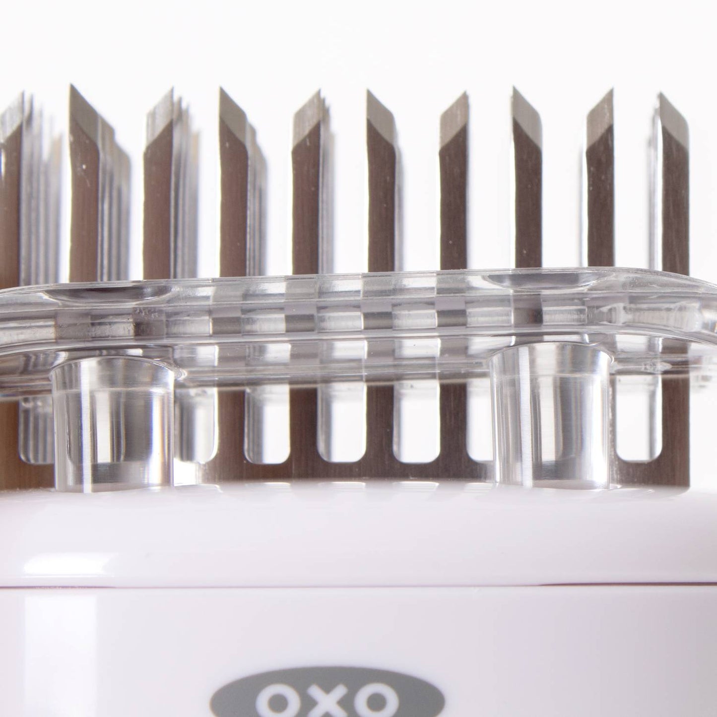 Close-up of stainless steel blades set in a clear protective cover on a white handheld meat tenderizer, part of Kitchen & Food, Specialty Equipment, and Butchering Supplies collections.