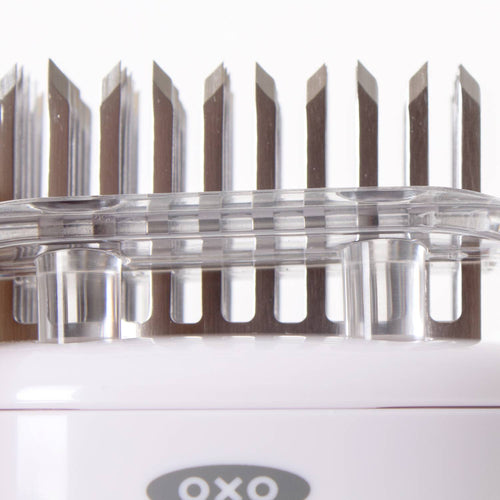 Close-up of stainless steel blades set in a clear protective cover on a white handheld meat tenderizer, part of Kitchen & Food, Specialty Equipment, and Butchering Supplies collections.