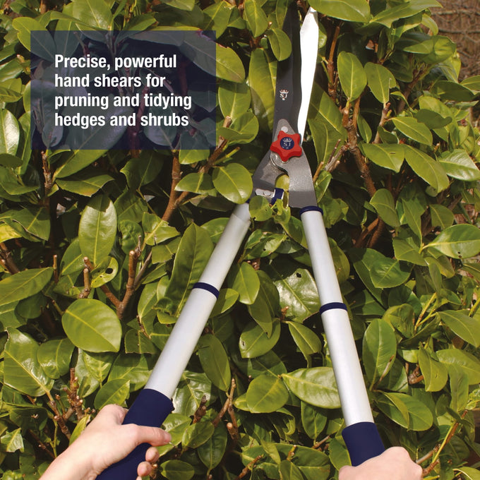 Telescopic aluminum hand shears with twist and lock handles extending for extra reach, shown pruning dense green shrubbery, part of Farm, Garden & Tool and Lawncare collections.