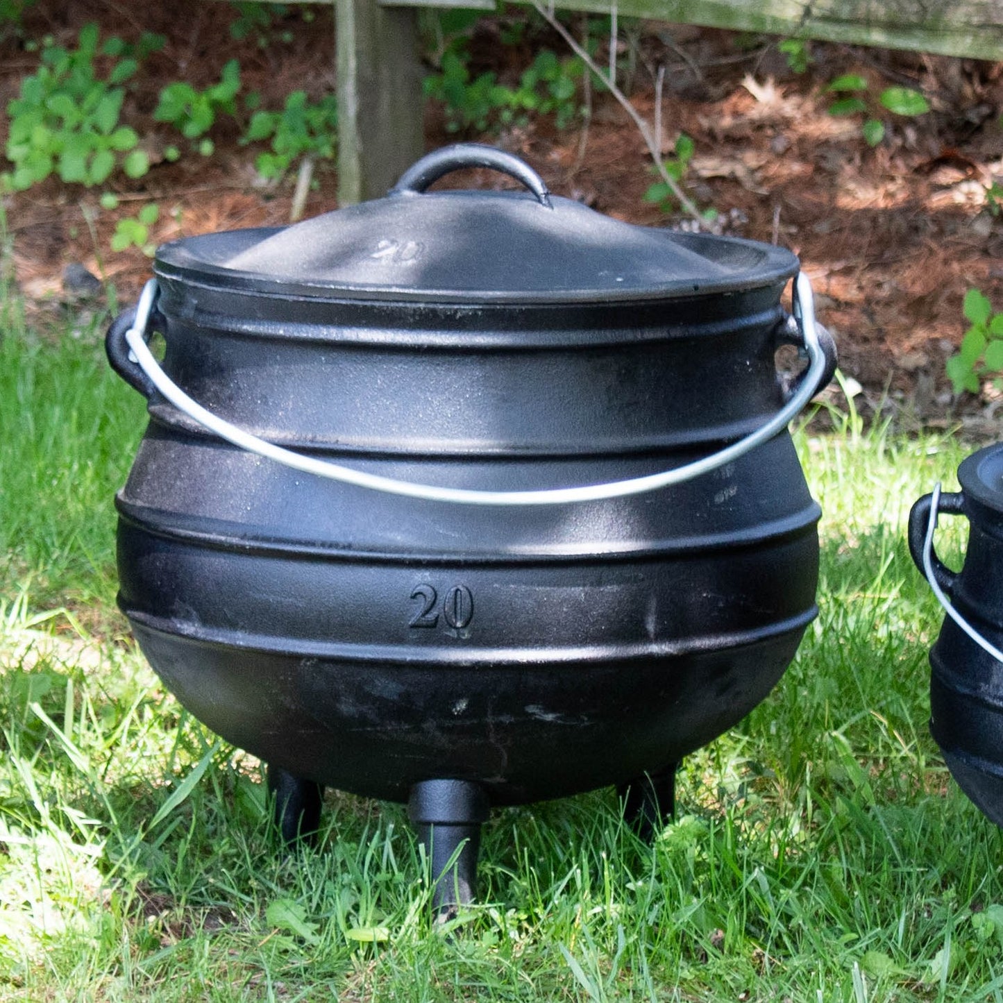 Handcrafted cast iron campfire kettle with a rounded, stepped body, fitted lid, sturdy wire bail handle, and three legs, ideal for outdoor cooking in Farm, Garden & Tool, Camping, Best Sellers, and Promo Eligible collections.