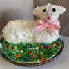 Handcrafted Easter lamb cake made using a unique aluminum baking pan with white frosting, textured coconut topping, pink bow, and decorated with colorful candy eggs on green shredded coconut, featured in Kitchen & Food, Cookware, Baking Supplies, USA Made, Best Sellers, and Promo Eligible collections.