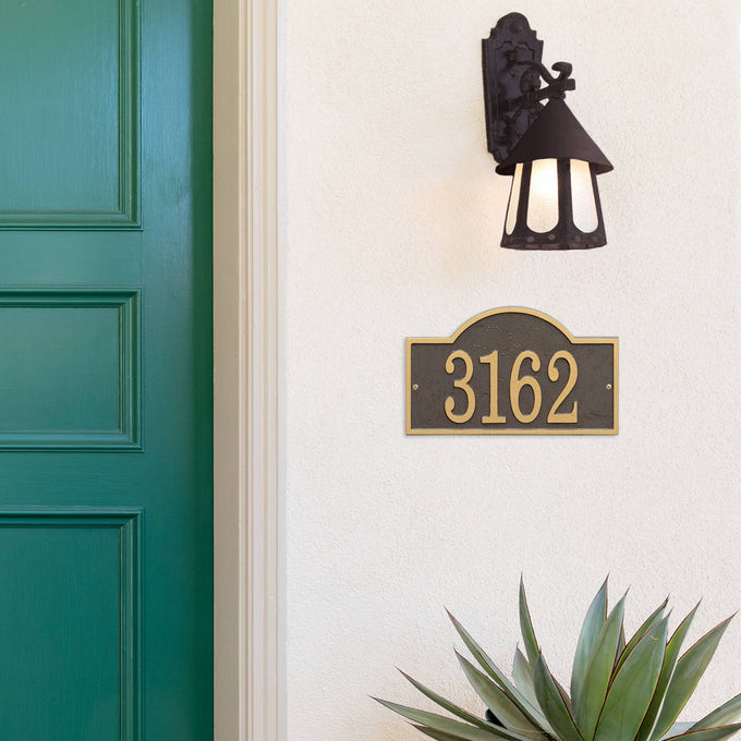 Custom bronze and gold arched rectangle address plaque with raised numbers mounted on a light stucco wall beneath a black vintage-style outdoor lantern, enhancing curb appeal in Home & Decor, USA Made, and Mailboxes and Address Signs collections.