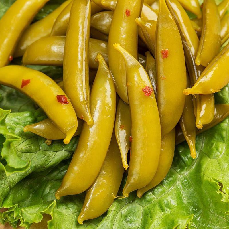 Close-up of handcrafted pickled snap peas with visible chili flakes, arranged on fresh green lettuce, highlighting USA made quality in Kitchen & Food and Pantry collections.