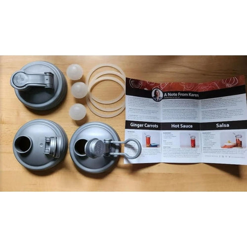 Set of three wide-mouth fermentation lids in gray with flexible silicone gaskets and airlock plugs, arranged alongside a printed recipe guide, ideal for Kitchen & Food and Food Preservation collections.
