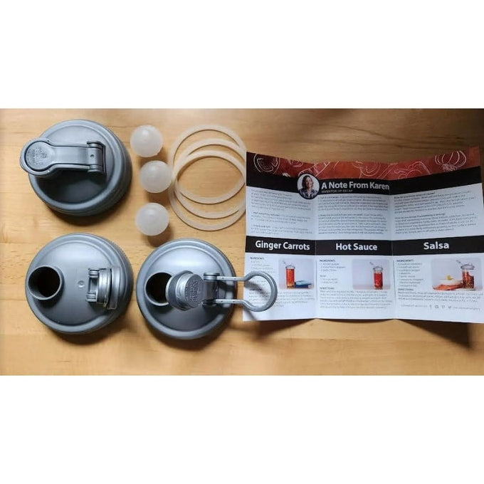 Set of three wide-mouth fermentation lids in gray with flexible silicone gaskets and airlock plugs, arranged alongside a printed recipe guide, ideal for Kitchen & Food and Food Preservation collections.