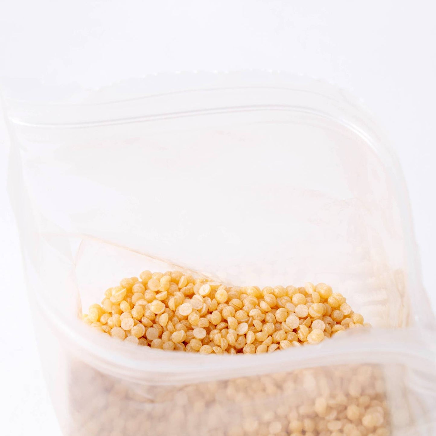 Bag of natural beeswax pellets in a resealable pouch, ideal for crafting pure beeswax candles, featured in candlemaking supplies and lamps and lighting collections.