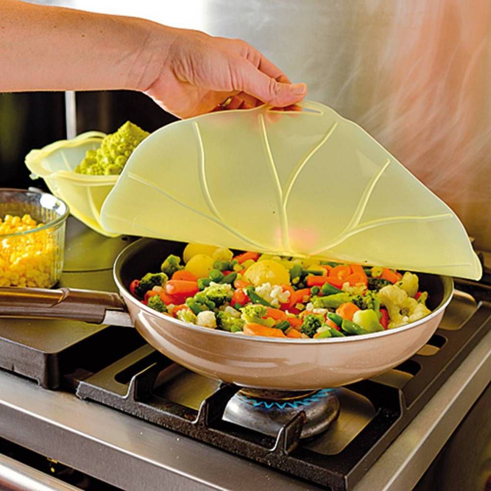 Handcrafted reusable silicone bowl cover with lilypad design being lifted off a skillet of steaming mixed vegetables on a gas stove, suitable for Kitchen & Food, Kitchen Gadgets, Cooking and Baking Helpers, Storage and Serving, Best Sellers, and Promo Eligible collections.