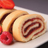 Close-up of a freshly sliced jelly roll cake with raspberry filling, garnished with fresh strawberries and raspberries, perfect for Kitchen & Food and Baking Supplies collections.
