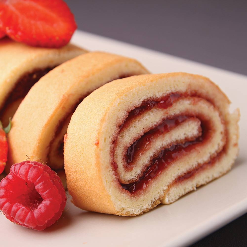 Close-up of a freshly sliced jelly roll cake with raspberry filling, garnished with fresh strawberries and raspberries, perfect for Kitchen & Food and Baking Supplies collections.