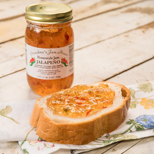 Handcrafted jalapeno jam jar with visible chili pieces beside a slice of bread spread with the jam, featured in Kitchen & Food, Pantry, USA Made, and Best Sellers collections.