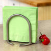 Upright stainless steel napkin holder with satin nickel finish holding green napkins on a kitchen countertop next to two small red peppers, ideal for Home & Decor and Kitchen & Food collections.